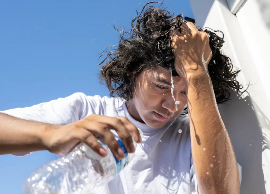 Beckman High School band member Adan Martinez, 17, cools off...