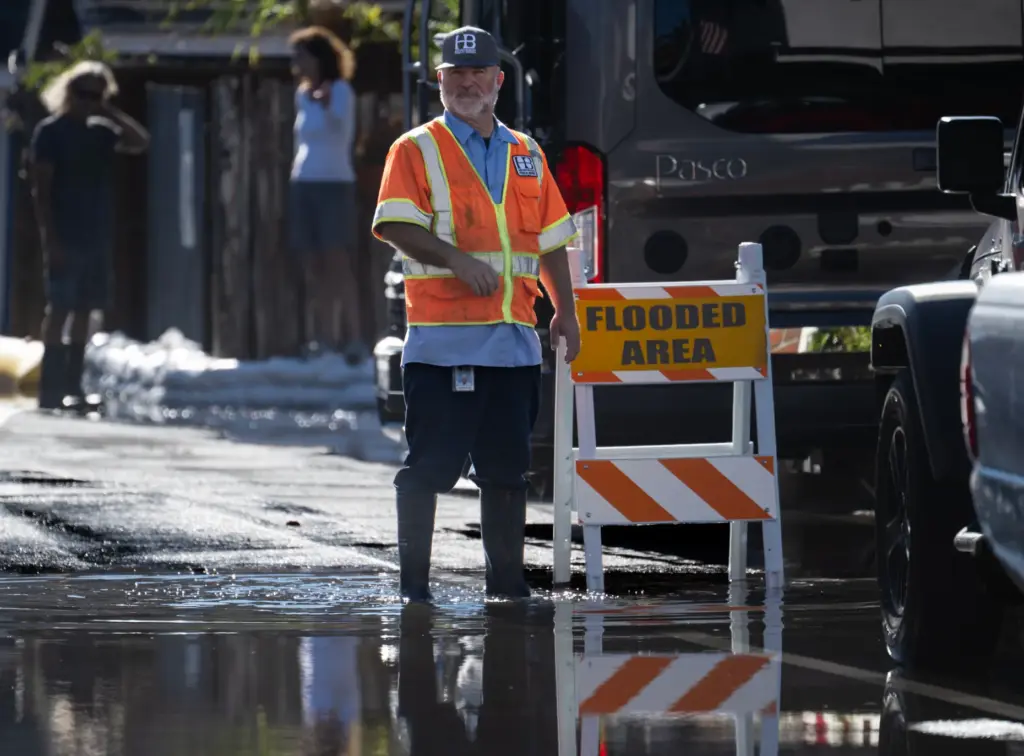 City workers put up caution signs and pump water off...