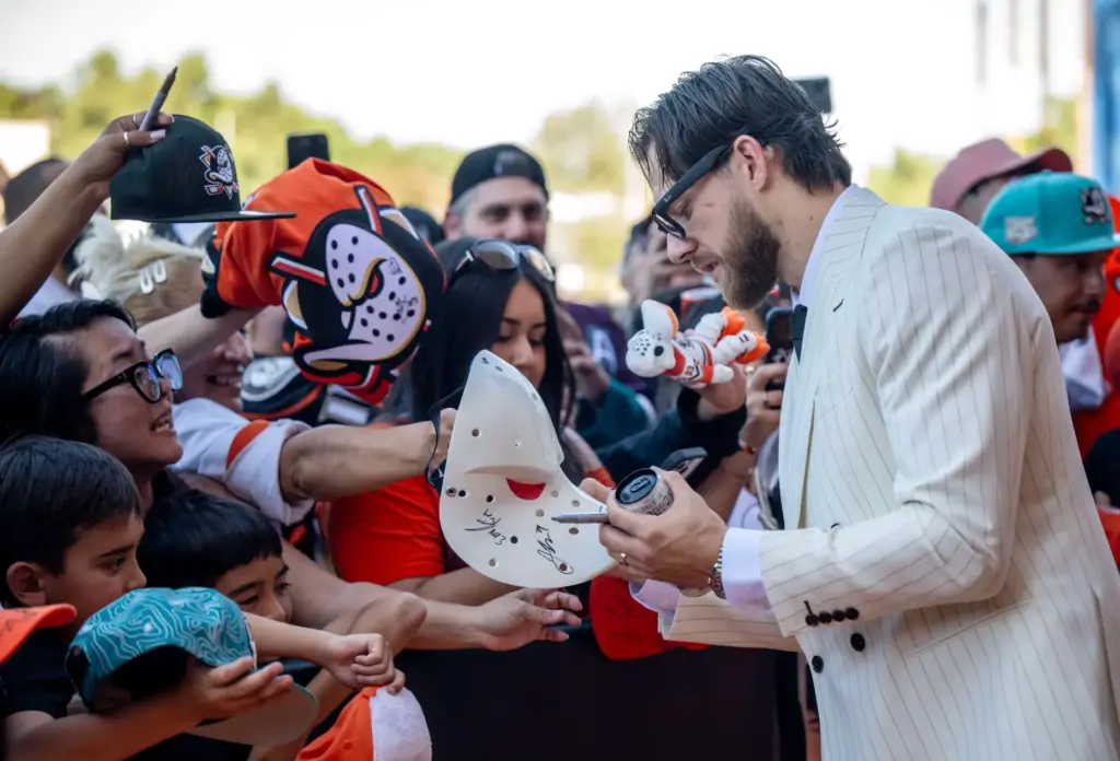 Ducks player A.J. Greer signs autographs on the orange carpet...