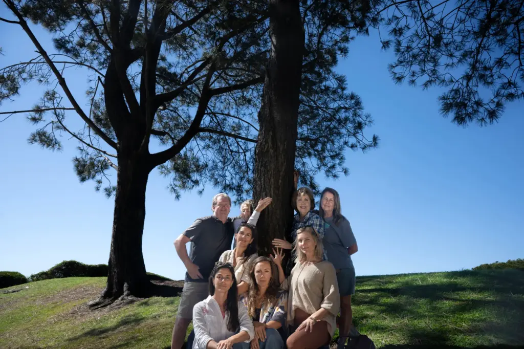 A group of residents stands next to Torrey pines, a...
