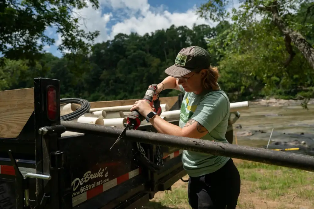 A worker from MountainTrue cuts IPEX PVC pipe taken from...