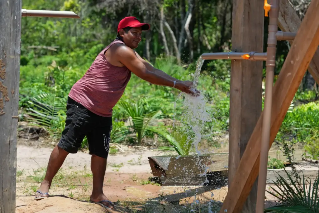Arapium Indigenous leader Tiago Silva cools off with water pumped...