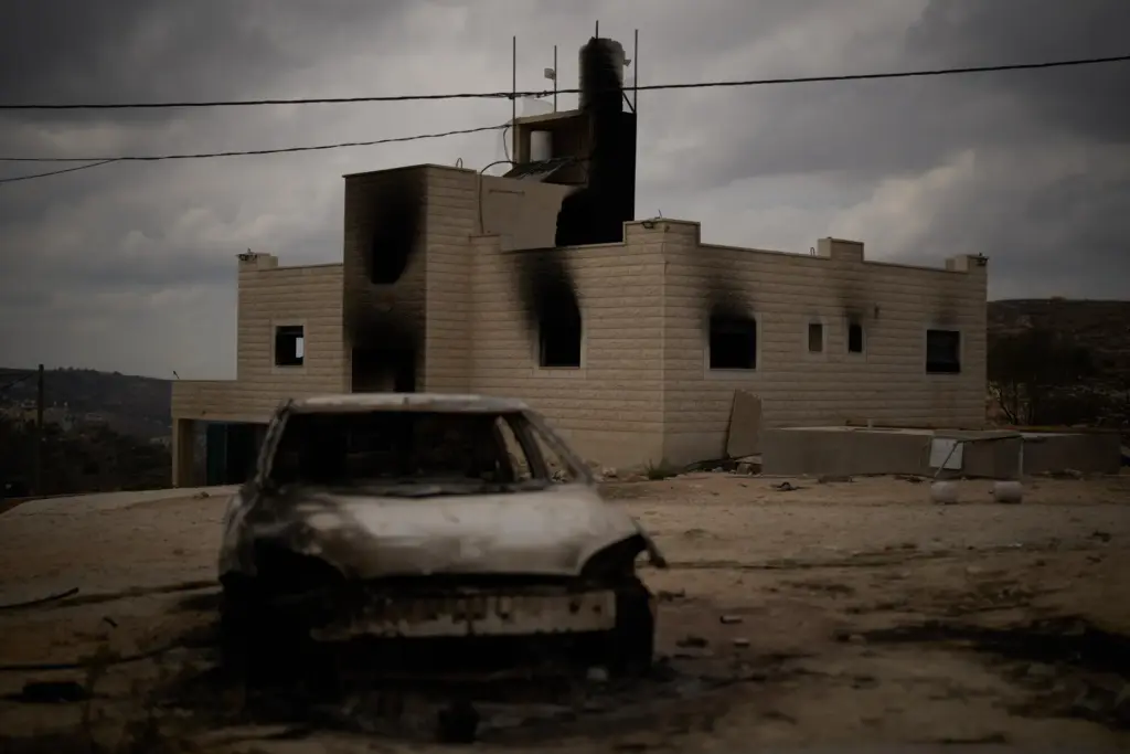FILE – A burnt car is seen in front of...