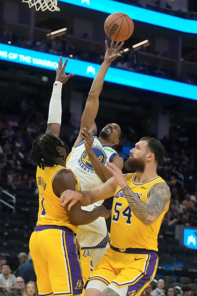 Golden State Warriors guard De’Anthony Melton, middle, shoots in front...