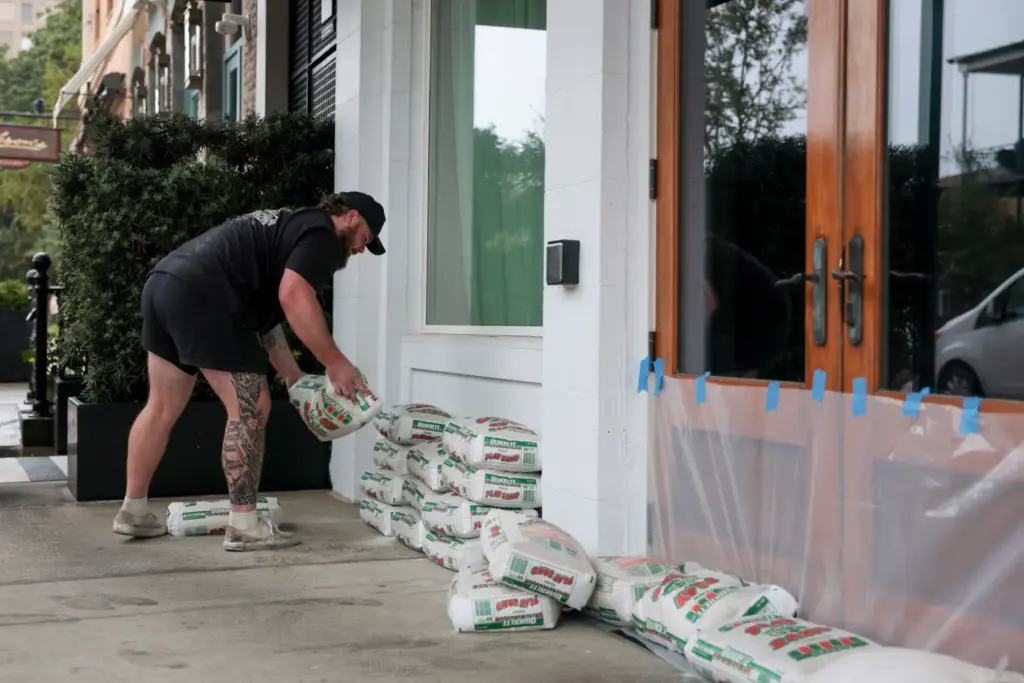 Chris Essex places sandbags in front of a business as...