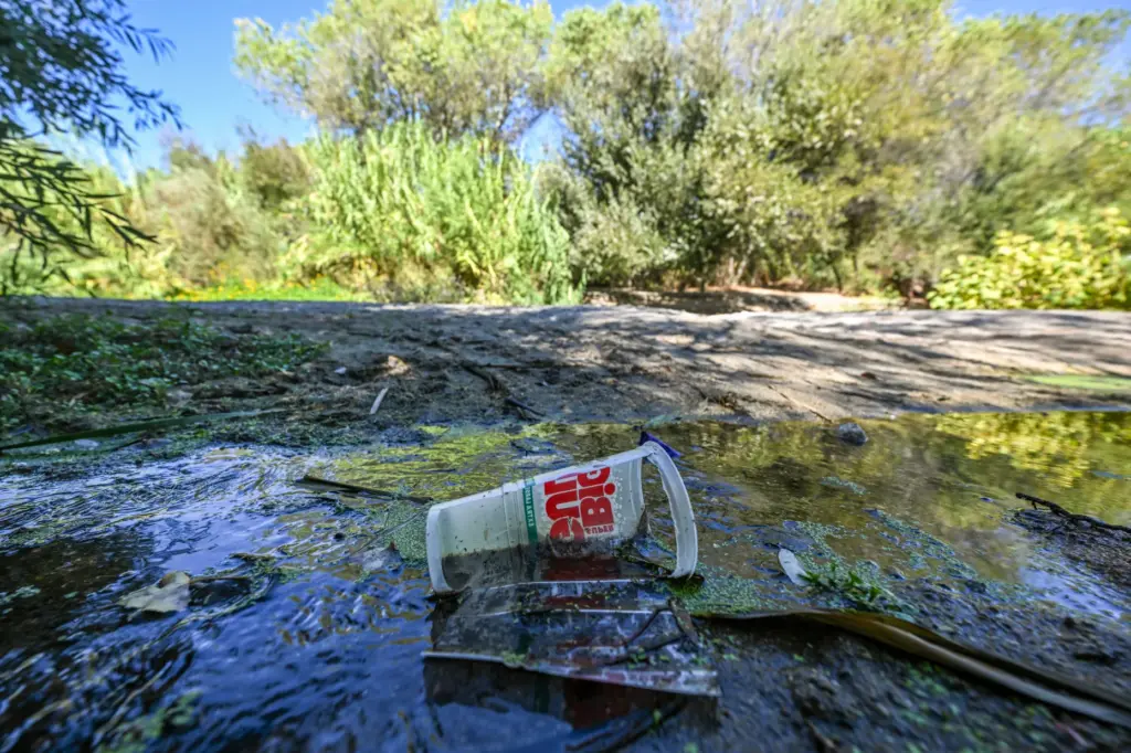 Trash sits in the water as the Santa Ana River...