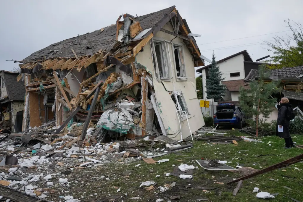 A woman looks at residential house destroyed in a Russian...
