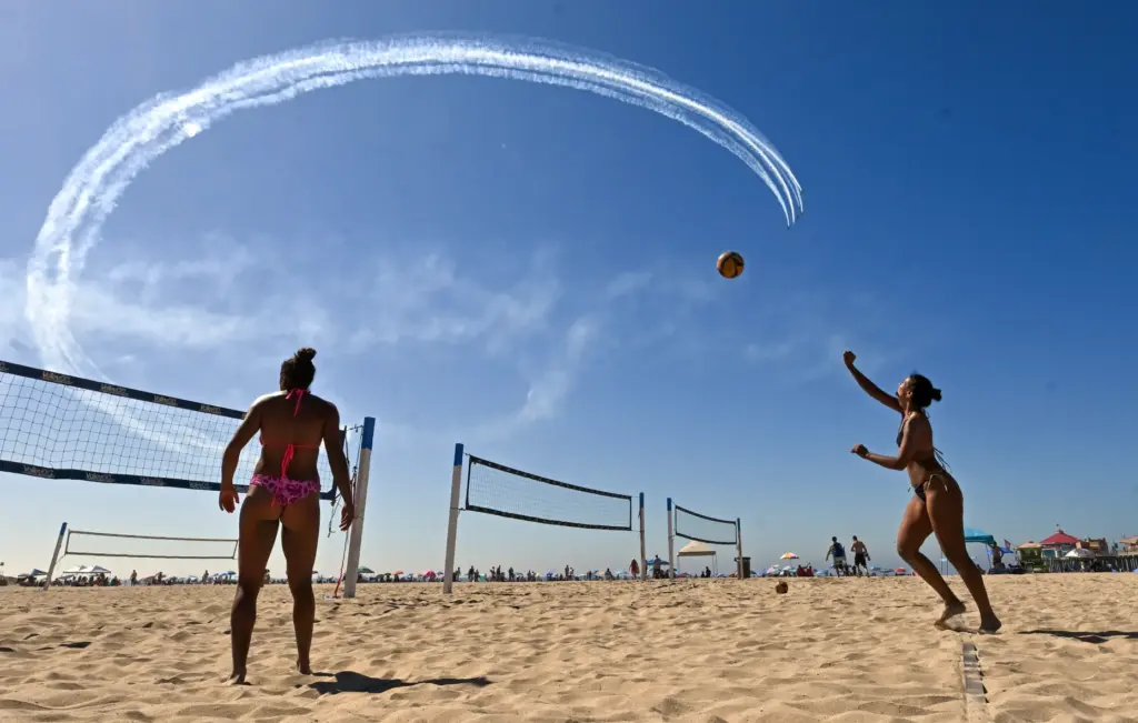 Beachgoers play volleyball as the Dawn Patrol Airshows Formation Team...
