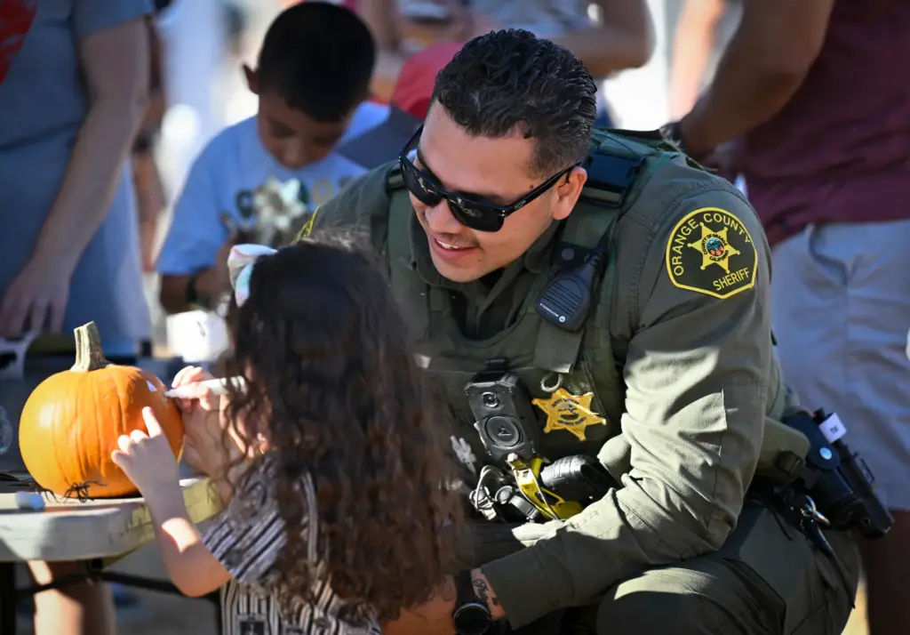 Armando Montalvo of the Orange County Sheriffâs Department, right, helps...