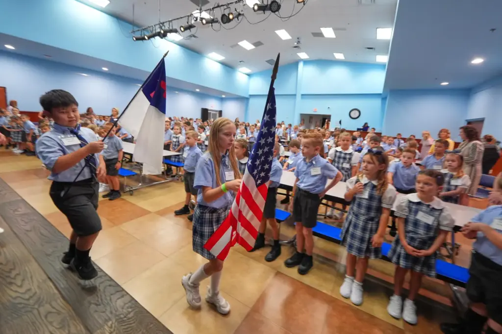 Children at Covenant Christian Academy carry flags during chapel.