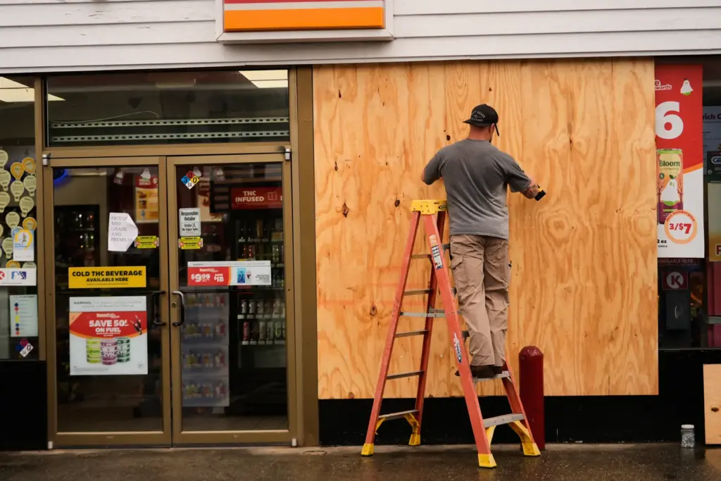 Jason Coffey boards up a convenience store at a gas...