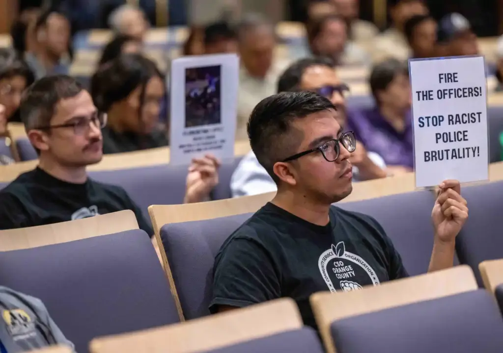Members of the public hold up signs critical of the...