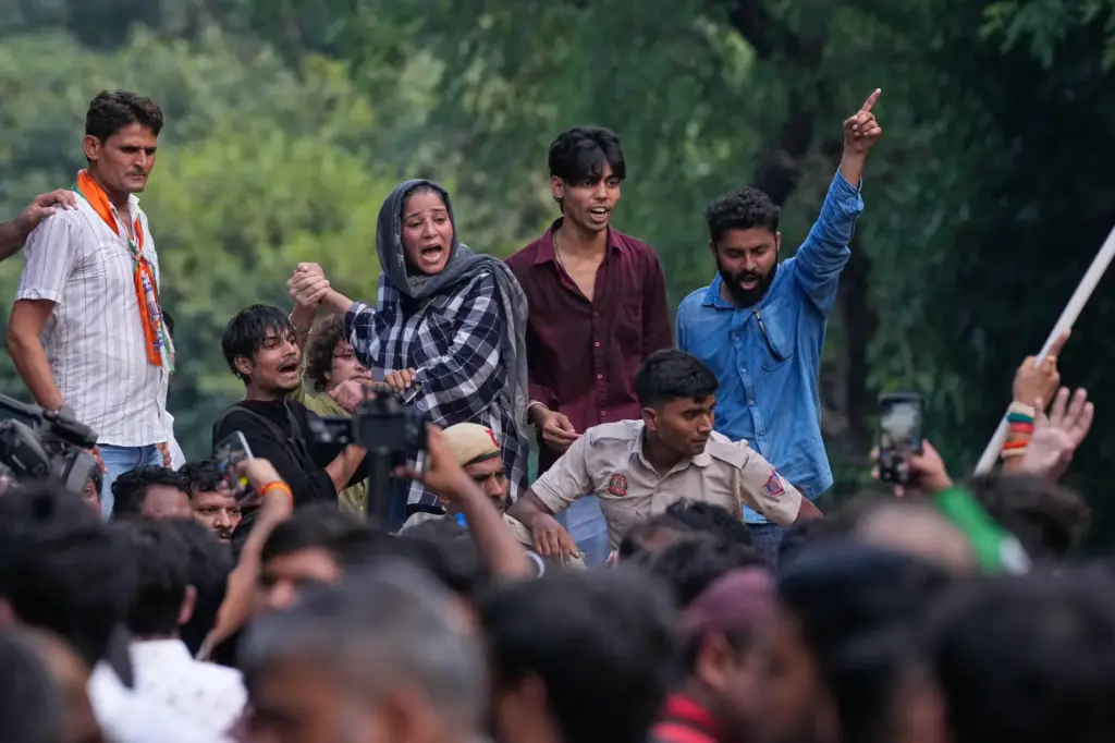 Activists shout slogans as they climb onto a police barricade during a protest march.