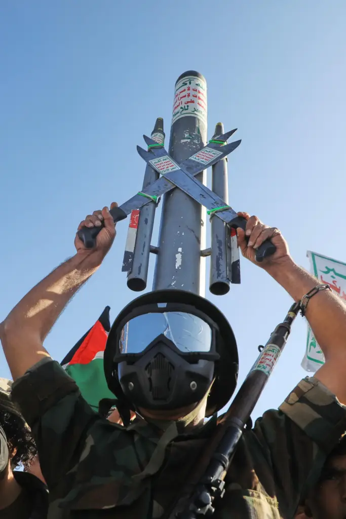 A Houthi supporter wearing a military uniform holds a mock...