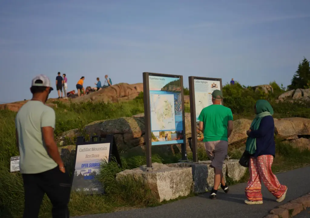 Visitors read signs at the summit of Cadillac Mountain in...