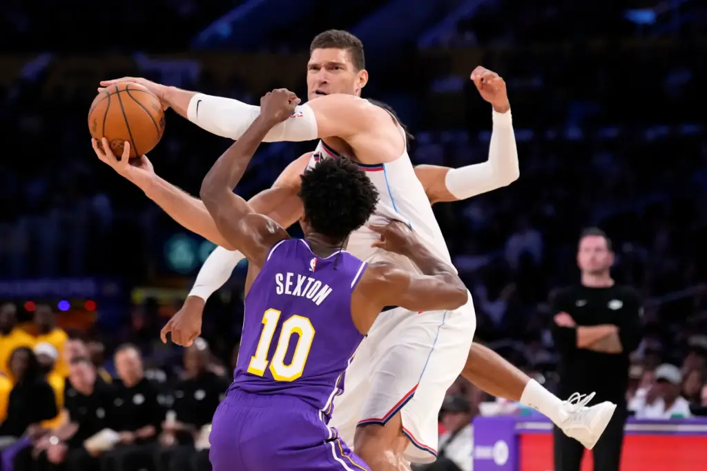 Clippers center Brook Lopez, center, tries to pass the ball...