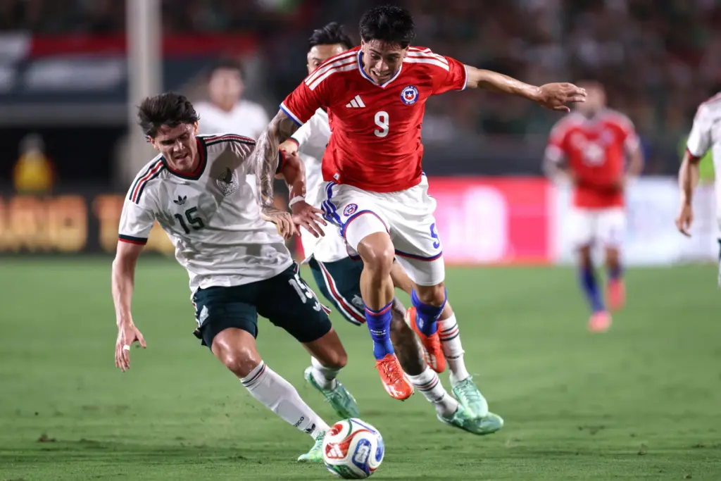 Chile forward Maximiliano GutiÃ©rrez, right, jumps in the air to...