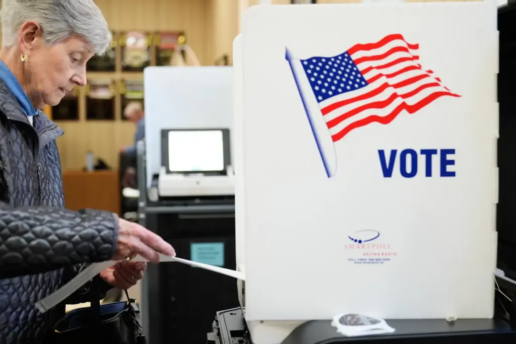A woman feeds her ballot into a scanning machine at...