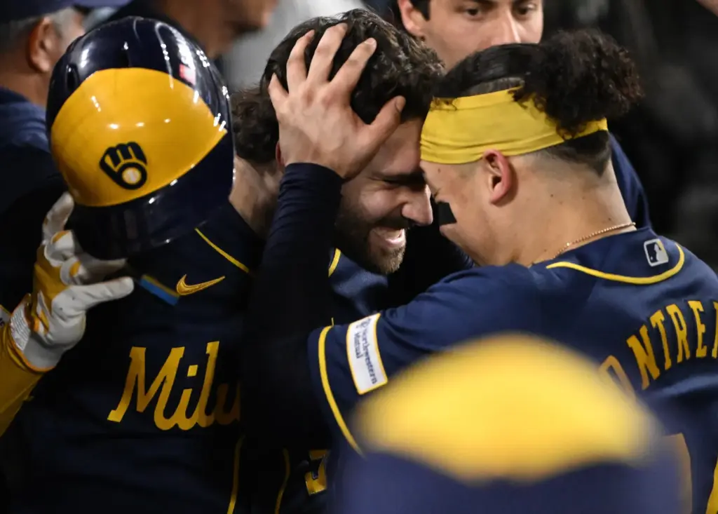 The Milwaukee Brewers’ Garrett Mitchell, left, celebrates in the dugout...