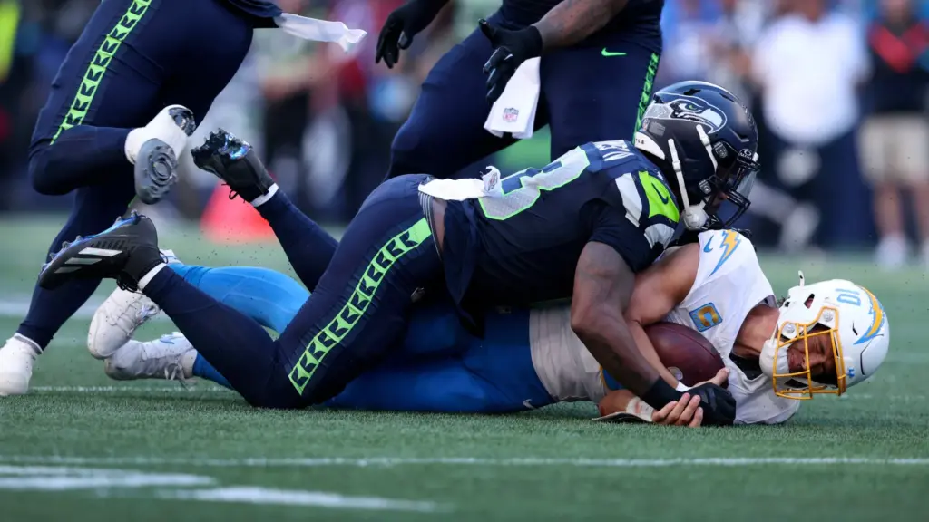 Chargers quarterback Justin Herbert (10) is tackled by Seattle Seahawks...
