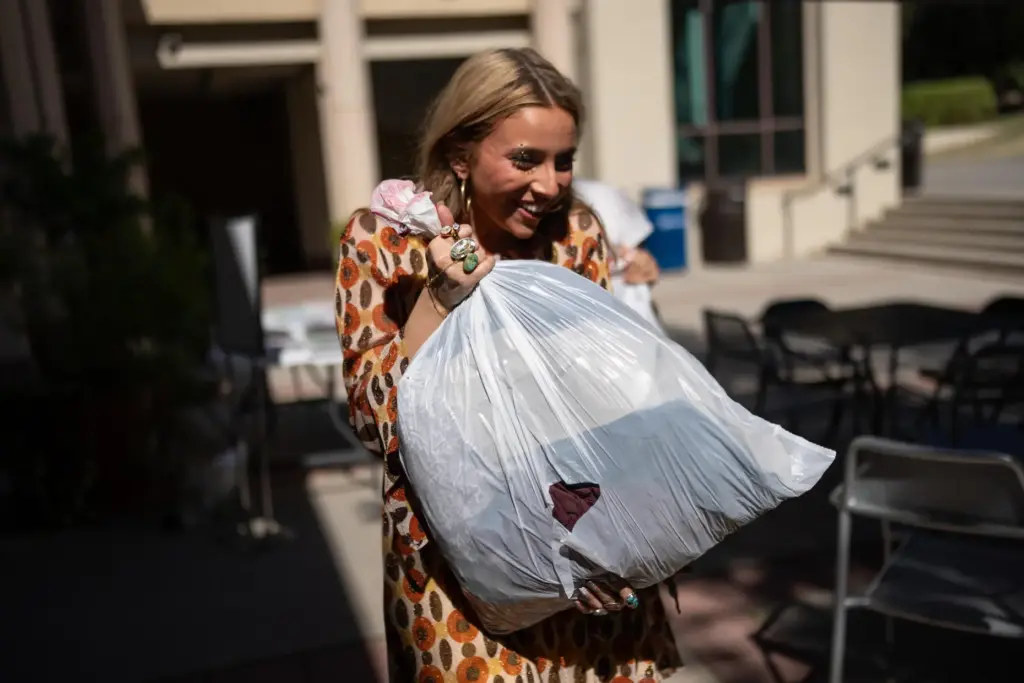Sustainable fashion advocate Lexy Silverstein smiles while carrying a bag...