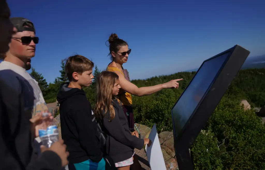 Visitors read a sign at the summit of Cadillac Mountain...