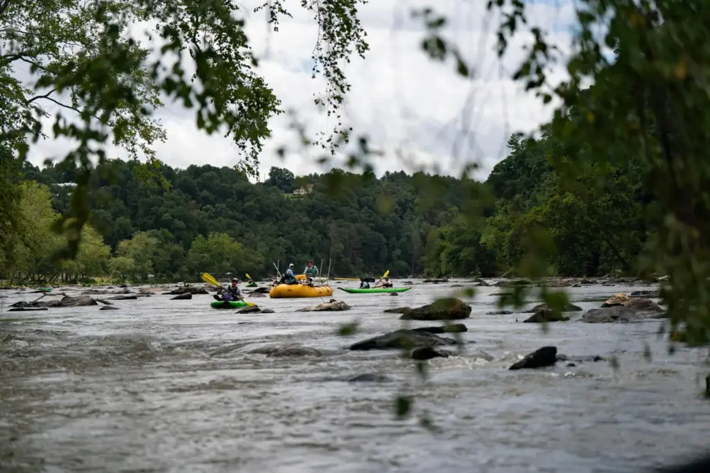 Workers from MountainTrue paddle IPEX PVC pipe they collected from the riverbank.