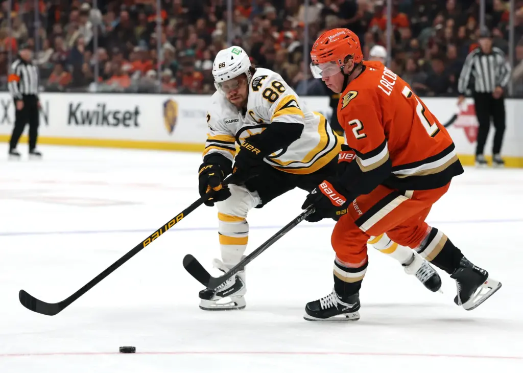 The Ducks’ Jackson LaCombe, right, and the Boston Bruins’ David...