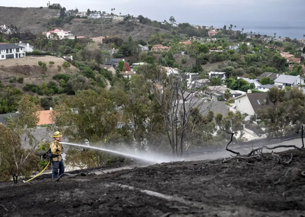 With a view of the ocean at right, a firefighter...