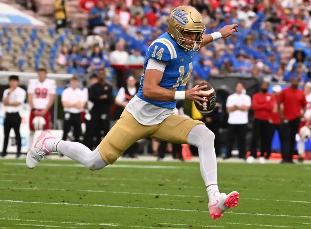 Quarterback Ty Dieffenbach #14 of the UCLA Bruins scrambles for...