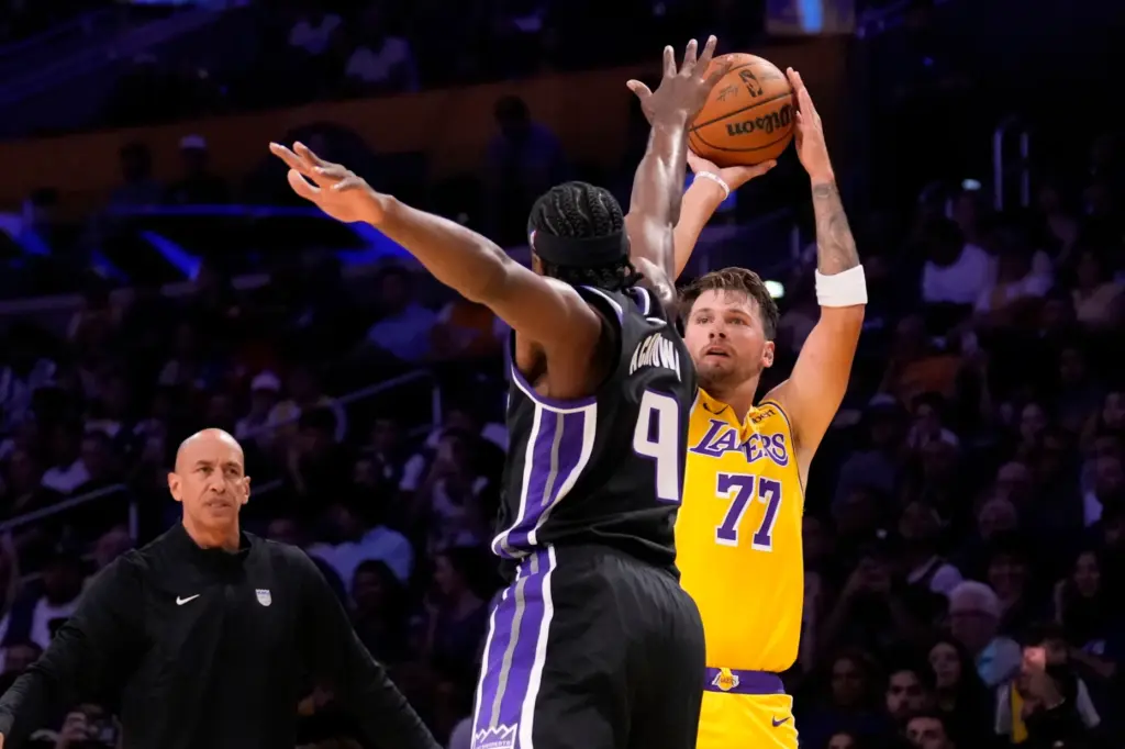 Lakers star Luka Doncic, right, shoots as Sacramento Kings forward...