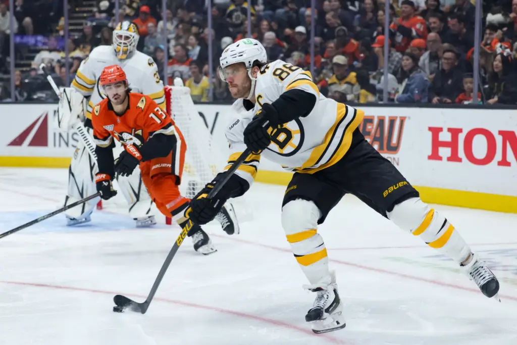 Boston Bruins right wing David Pastrnak, right, moves the puck...