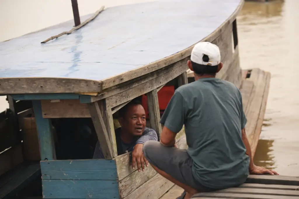 Abiansah, a boat operator, left, talks with a man at...