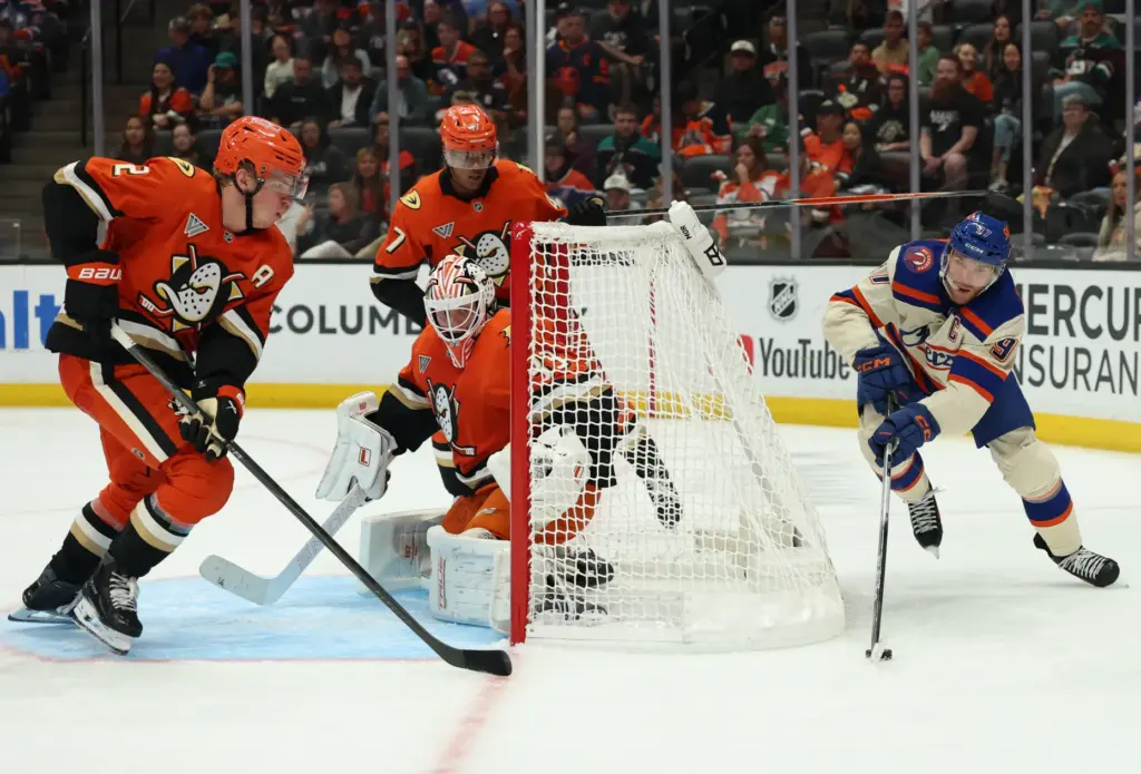 Edmonton Oilers star Connor McDavid, right, skates around the net...