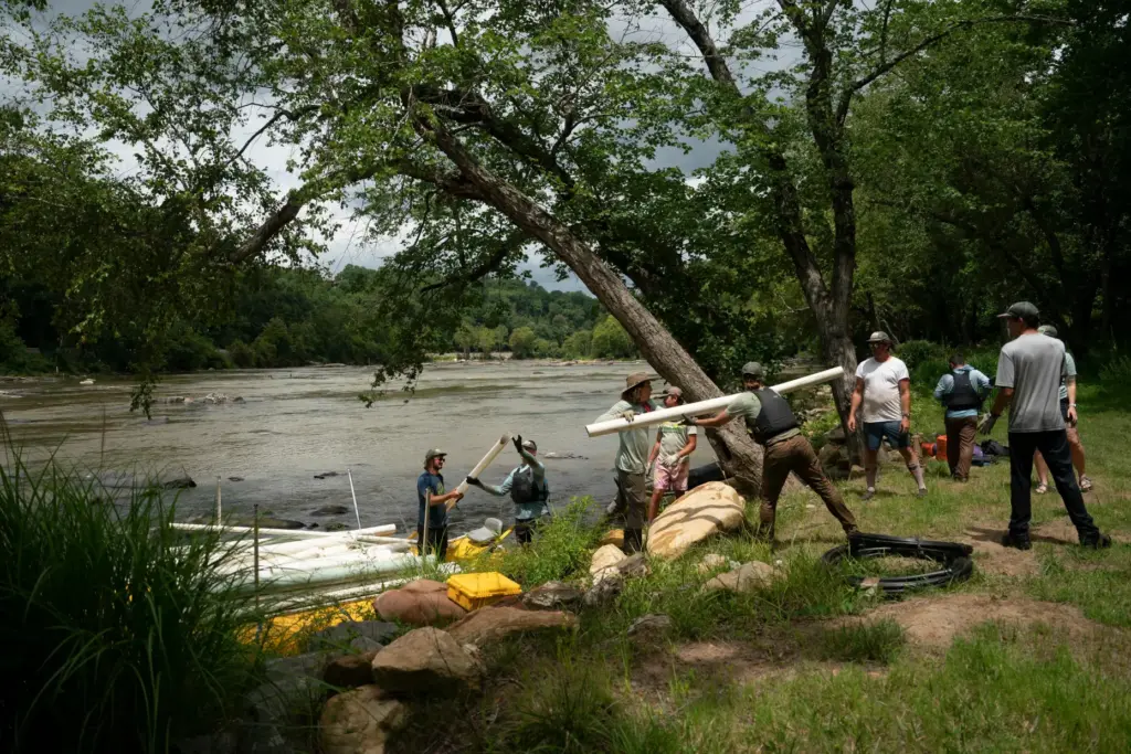Workers from MountainTrue paddle IPEX PVC pipe they collected from the riverbank.