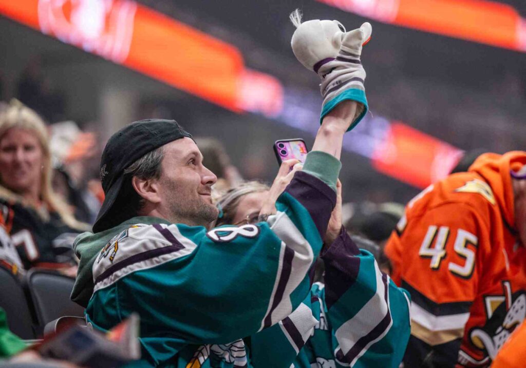 A Ducks fan cheers on the team while holding a...
