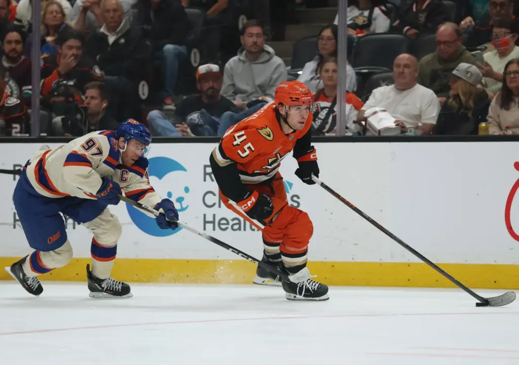 The Ducks’ Beckett Sennecke, right, pushes the puck up the...