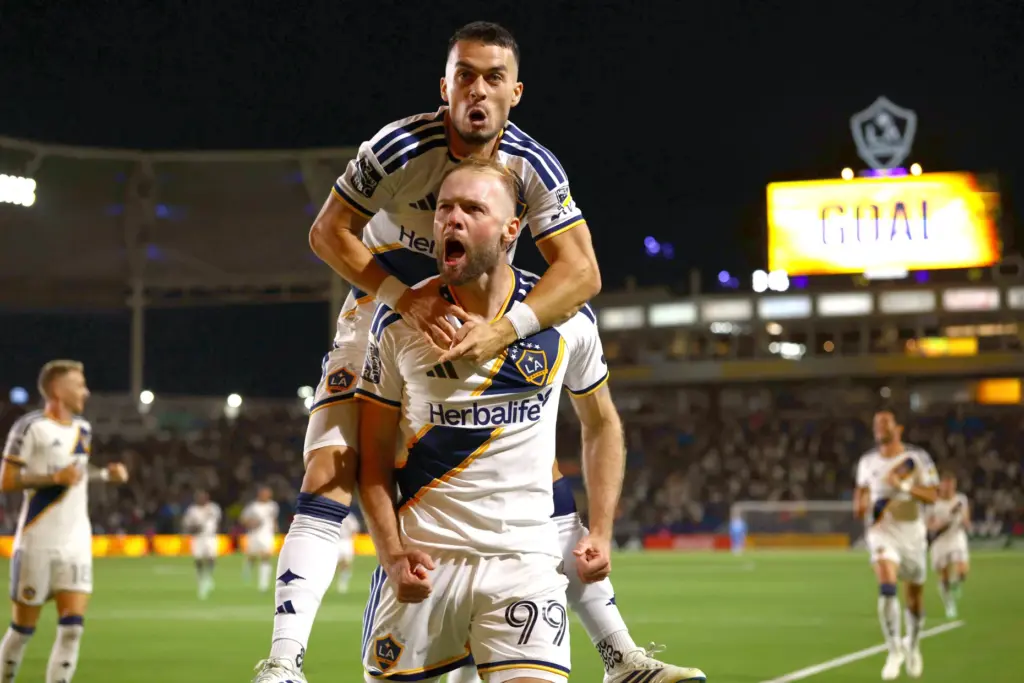 Los Angeles Galaxy midfielder Erik Thommy, top, jumps on teammate...