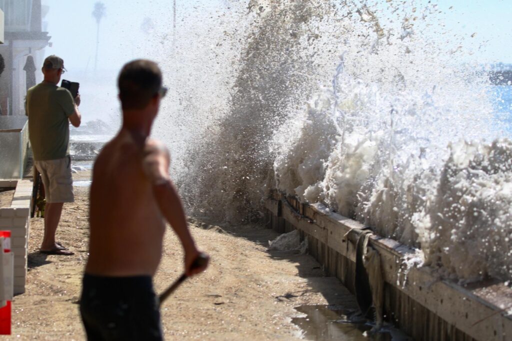 Waves crash into the Peninsula in Long Beach on Friday,...