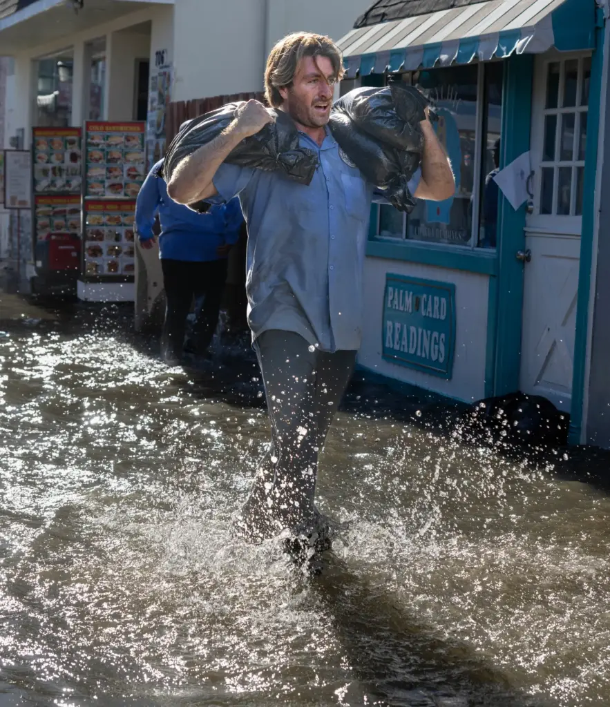 Newport Beach workers carry sandbags to fight flooding at the...