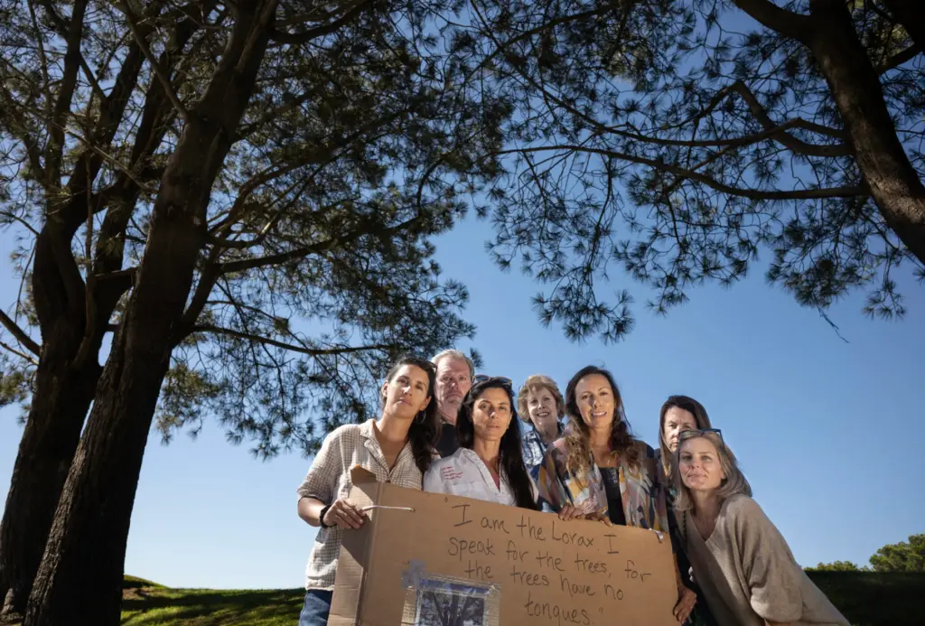 A group of residents stands next to Torrey pines, a...