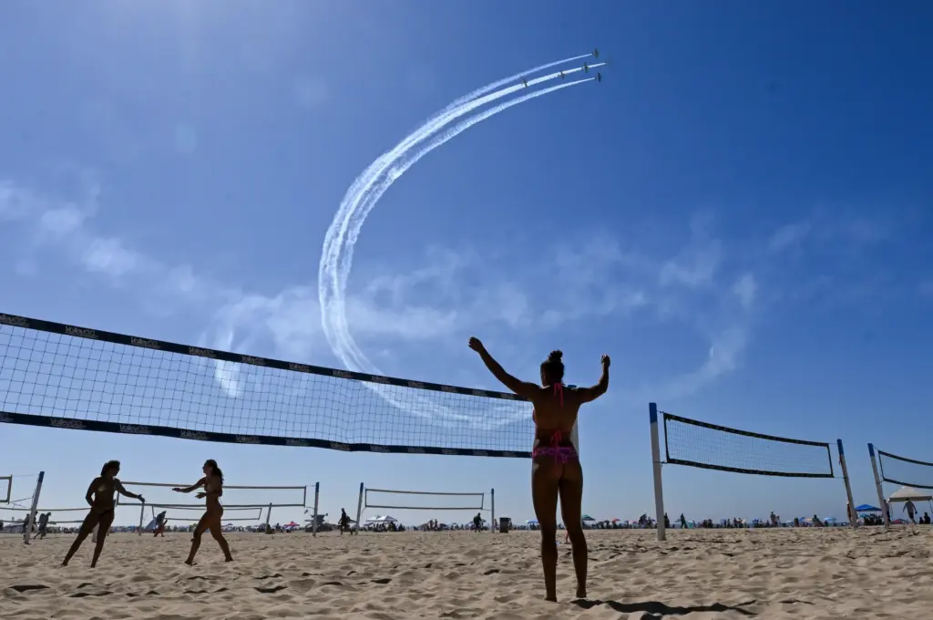 Beachgoers play volleyball as the Dawn Patrol Airshows Formation Team...