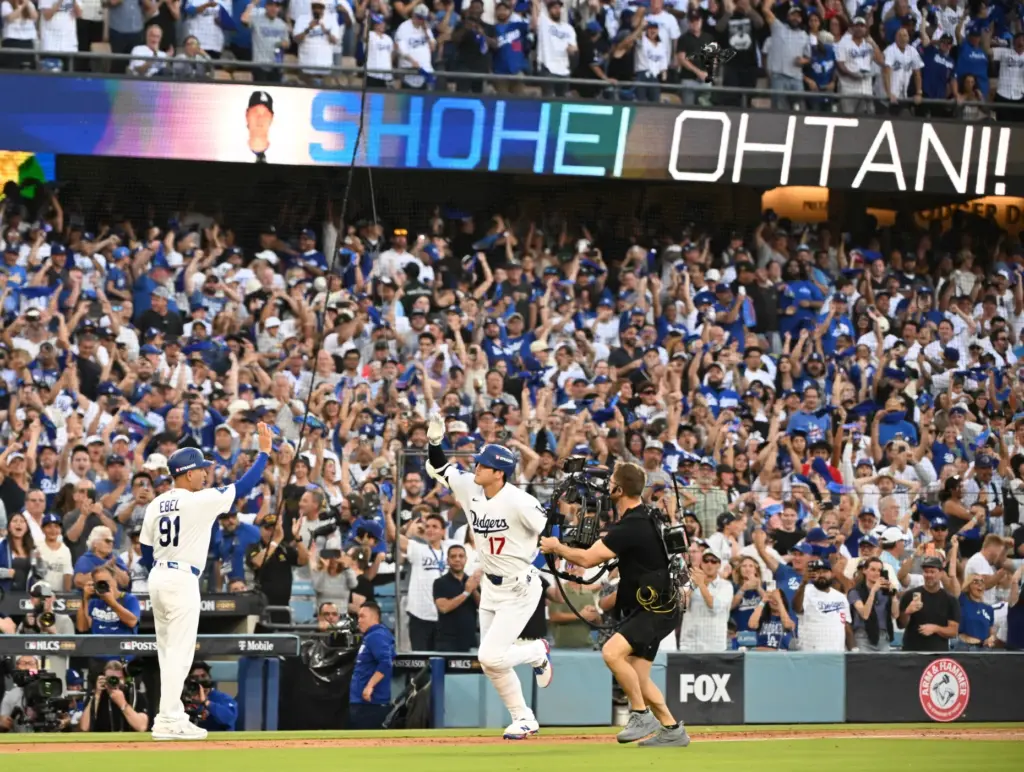 Dodgers star Shohei Ohtani, right, celebrates with third base coach...