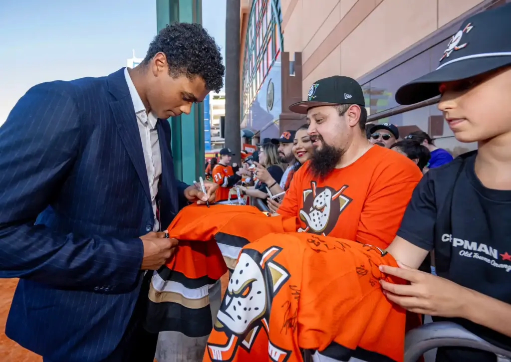 Ducks player Noah Warren signs autographs on the orange carpet...