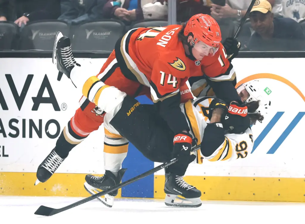 The Ducks’ Drew Helleson, top, checks the Boston Bruins’ Marat...