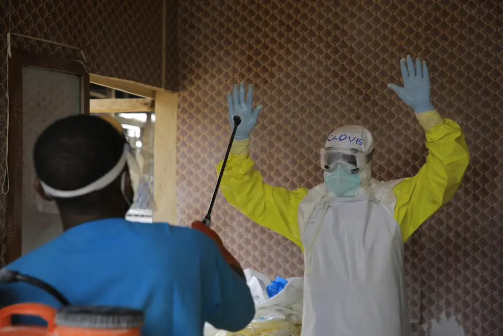 A healthcare worker is disinfected by a colleague inside a...