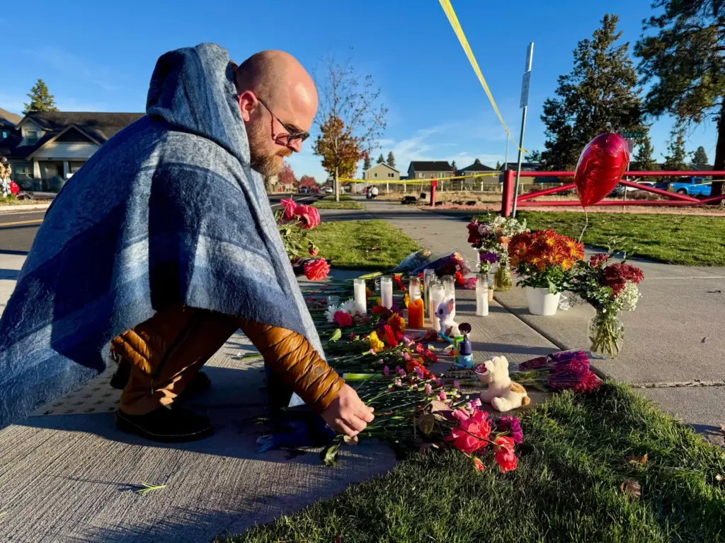 A person places flowers at a makeshift memorial on the...