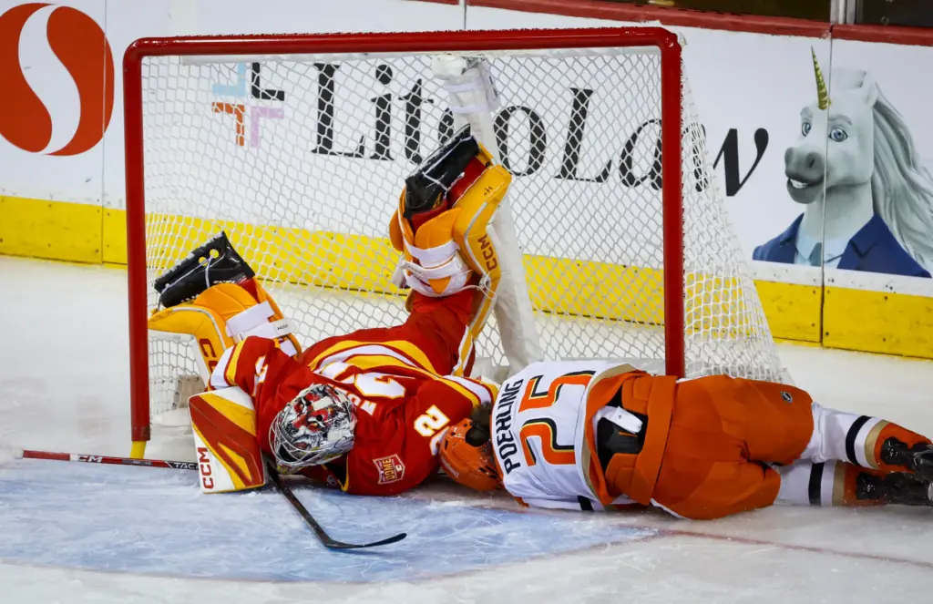 Ducks’ Ryan Poehling, right, crashes into the net knocking over...