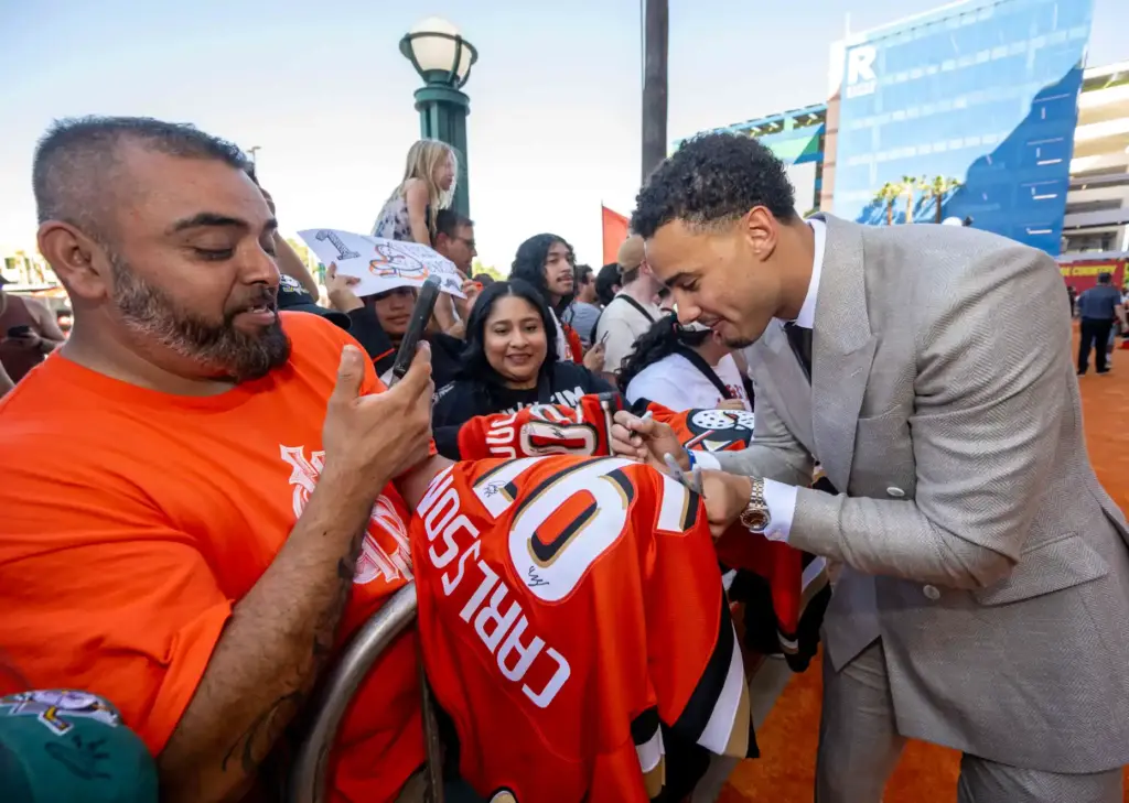 Ducks player Tyson Hinds signs autographs on the orange carpet...