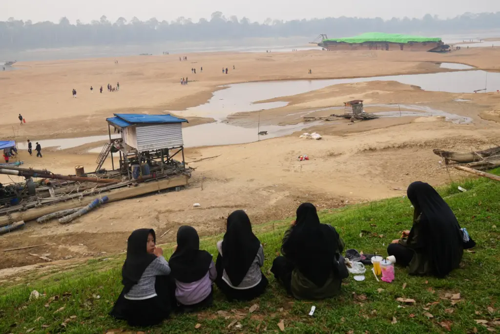 People look at a barge, back right, stranded on a...